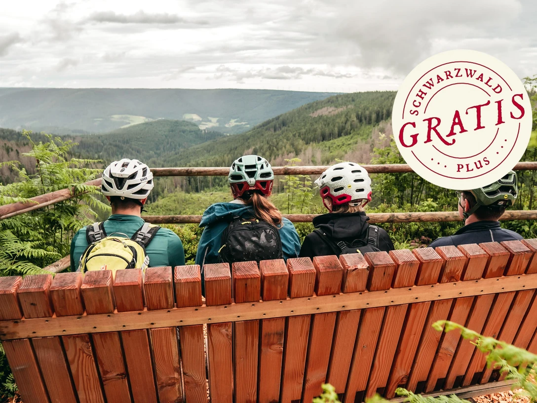 Mountainbiker sitzen auf einer Bank mit Ausblick