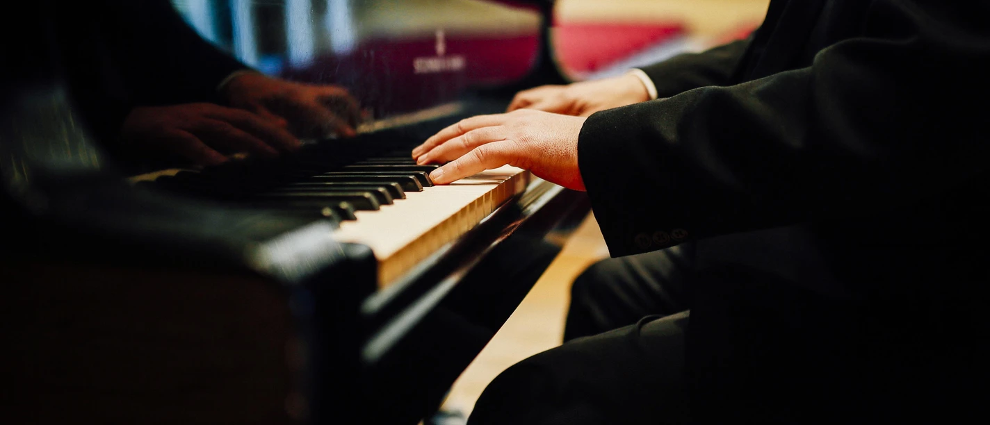Hände eines Pianisten spielen auf einem Flügel in der Konzerthalle.