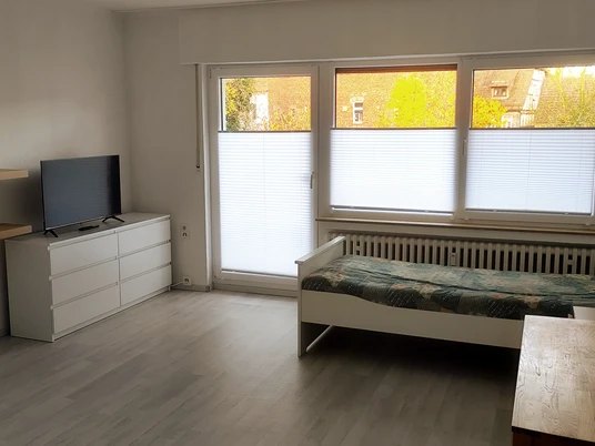 Schlafzimmer mit Einzelbett, Kommode und FernseherBedroom with single bed, chest of drawers and TV