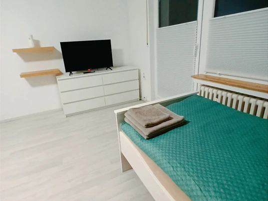 Schlafzimmer mit Einzelbett, Kommode und FernseherBedroom with single bed, chest of drawers and TV