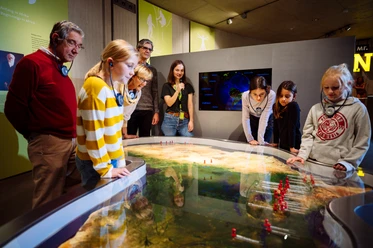 Mit Oma und Opa in die Steinzeit Kinder und Erwachsene studieren gemeinsam eine interaktive Karte der Steinzeit in einem Museum.