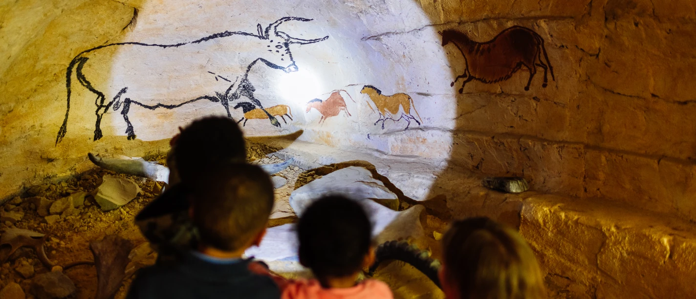 Steinzeitlicht und Höhlenblick Kinder betrachten fasziniert Höhlenmalereien mit Tieren in einer beleuchteten Höhle aus der Steinzeit.