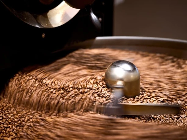 EOS3.jpg Kaffeebohnen werden in einer Röstmaschine gerührt, während sie eine goldene Farbe annehmen.