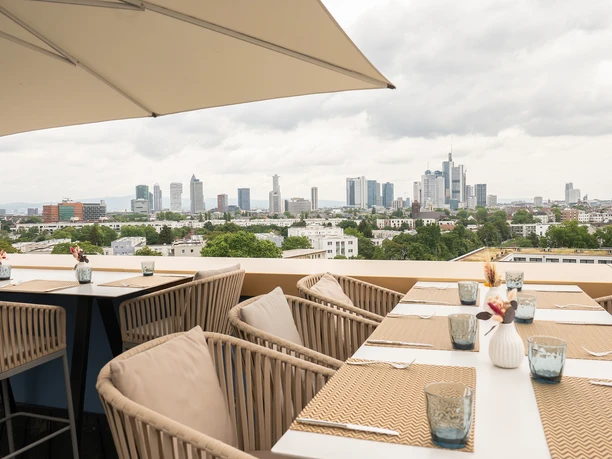Dachterrasse mit gedeckten Tischen und Blick auf Skyline Frankfurt