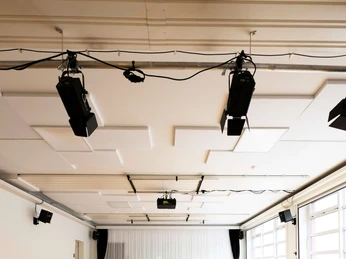 Un-Label Ein heller Tanzsaal mit Parkettboden, großen Fenstern und schallisolierten Deckenplatten.A bright dance hall with parquet flooring, large windows and soundproofed ceiling panels.