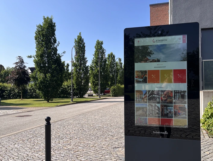 Infostele PS.SPEICHER Digitale Infostele vor dem PS.SPEICHER in Einbeck bei Sonnenschein. Im Hintergrund der Parkplatz des PS.SPEICHER mit Begrünung und Bäumen.