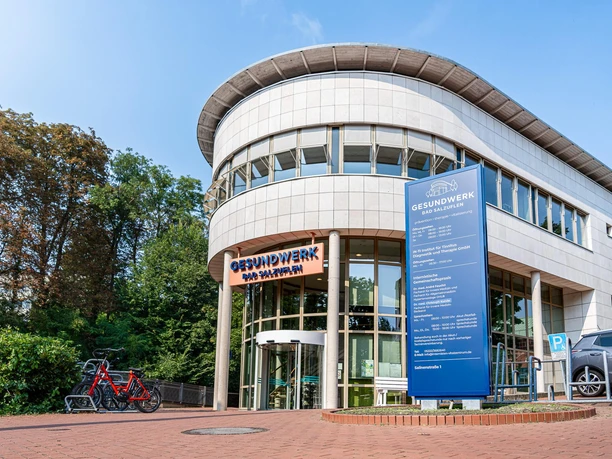 Eingang des Gesundwerks Bad Salzuflen mit Glasfassade, Schild, Fahrrädern und Parkplatz