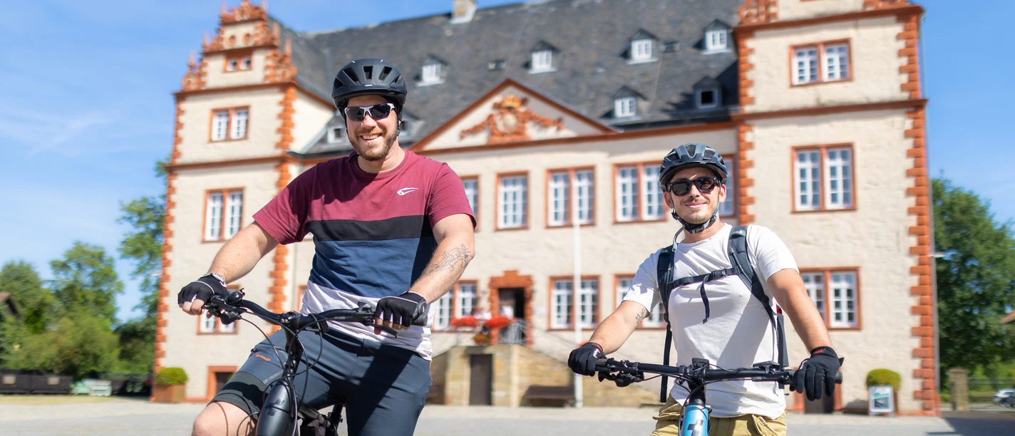 Das Bild zeigt zwei Radfahrer vor dem Schloss Salder