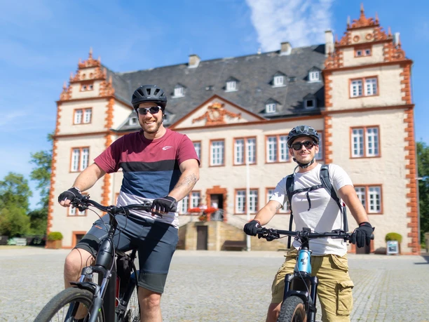 Das Bild zeigt zwei Radfahrer vor dem Schloss Salder