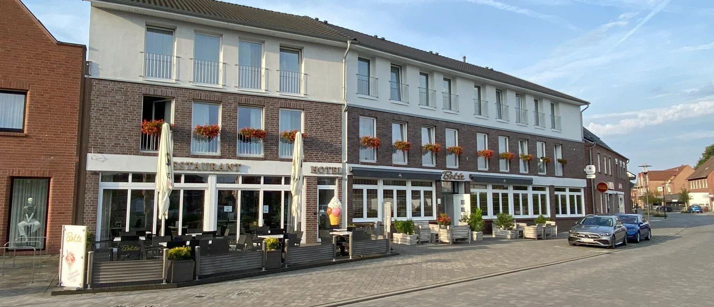 ©Gemeinde Salzbergen Modernes dreistöckiges Hotel-Restaurant mit Außenterrasse und Blumen an den Fenstern in Salzbergen.