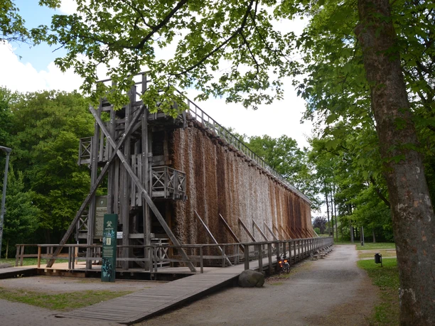 Gradierwerk Sielpark (c) K. Quest Ein hölzernes Gradierwerk im Park, umgeben von grünen Bäumen, mit einem Weg und Fahrrädern daneben.