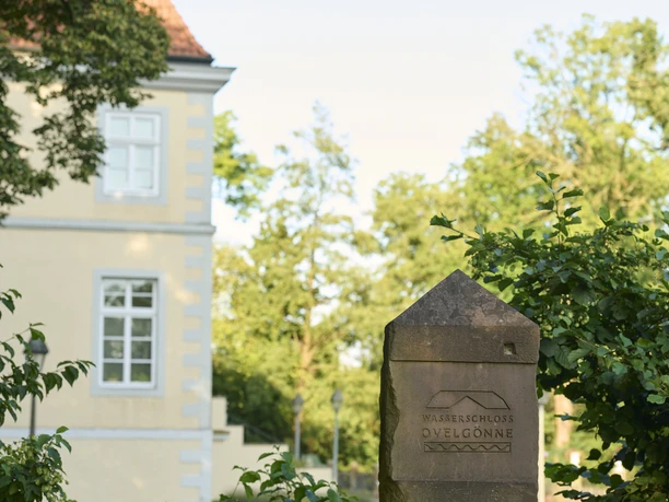 Wasserschluss Ovelgönne (c) Peter Hübbe Das Foto zeigt einen Stein mit der Inschrift "Wasserschloss Ovelgönne" vor einem historischen Gebäude.
