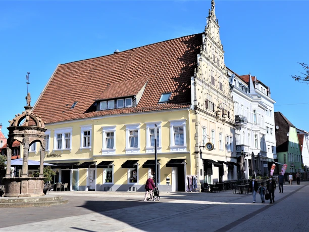 Neustädter Rathaus in Herford mit historischem Brunnen im Vordergrund an einem sonnigen Tag.
