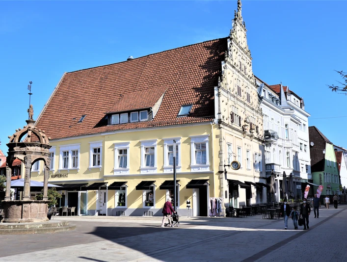 Neustädter Rathaus in Herford mit historischem Brunnen im Vordergrund an einem sonnigen Tag.