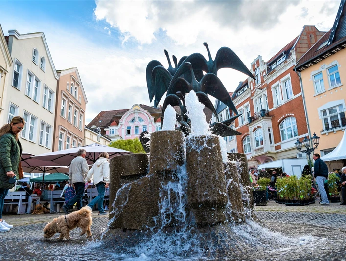 Brunnen mit Wasserspiel und umgeben von historischen Gebäuden auf dem lebhaften Gänsemarkt in Herford.