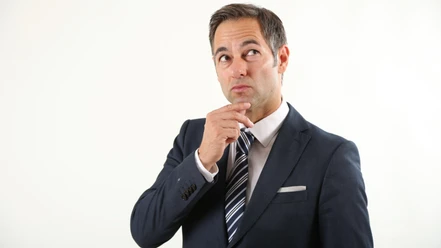 thieß-neubert.png Mann in Anzug mit nachdenklichem Blick, hält eine Hand ans Kinn vor hellem Hintergrund.