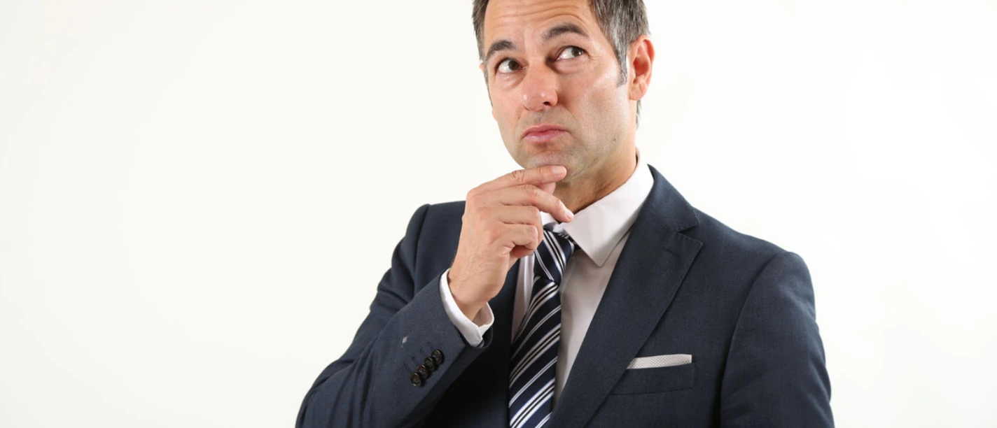 thieß-neubert.png Mann in Anzug mit nachdenklichem Blick, hält eine Hand ans Kinn vor hellem Hintergrund.