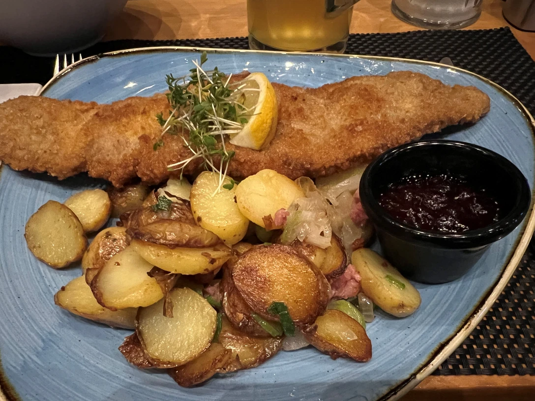 Ein knuspriges Wiener Schnitzel begleitet von goldbraunen Bratkartoffeln und Preiselbeeren.A crispy Wiener schnitzel accompanied by golden brown fried potatoes and cranberries.En sprød wienerschnitzel ledsaget af gyldenbrune stegte kartofler og tranebær.Een knapperige Wiener schnitzel vergezeld van goudbruin gebakken aardappelen en veenbessen.
