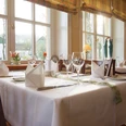 Gasthof Potthoff_004.jpg Ein helles, einladendes Restaurant mit elegant gedeckten Tischen und großen Fenstern im Hintergrund.