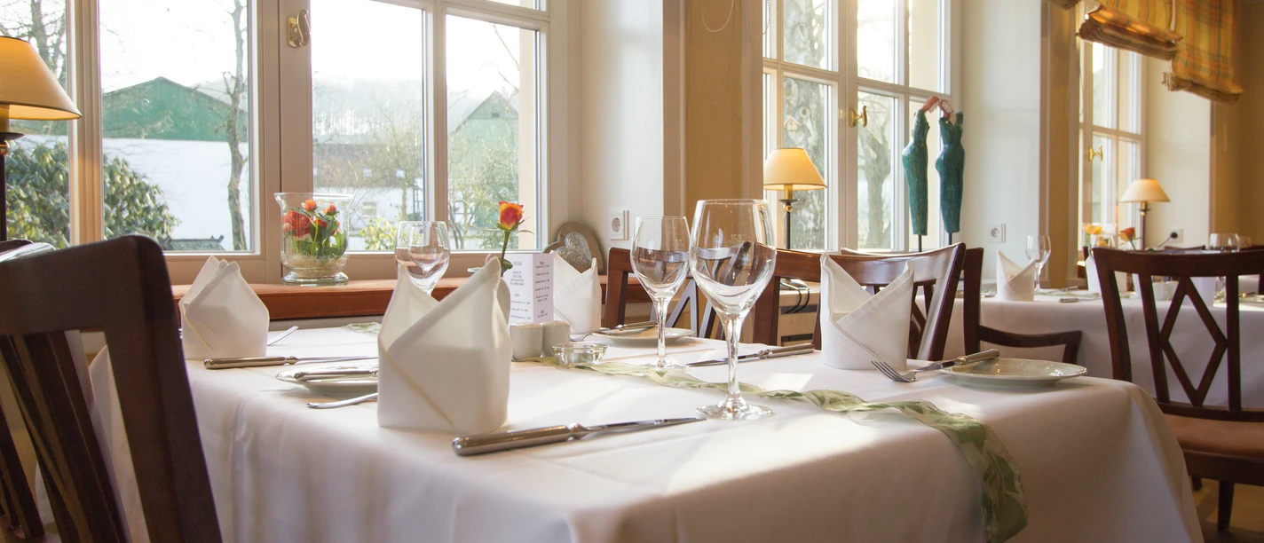 Gasthof Potthoff_004.jpg Ein helles, einladendes Restaurant mit elegant gedeckten Tischen und großen Fenstern im Hintergrund.