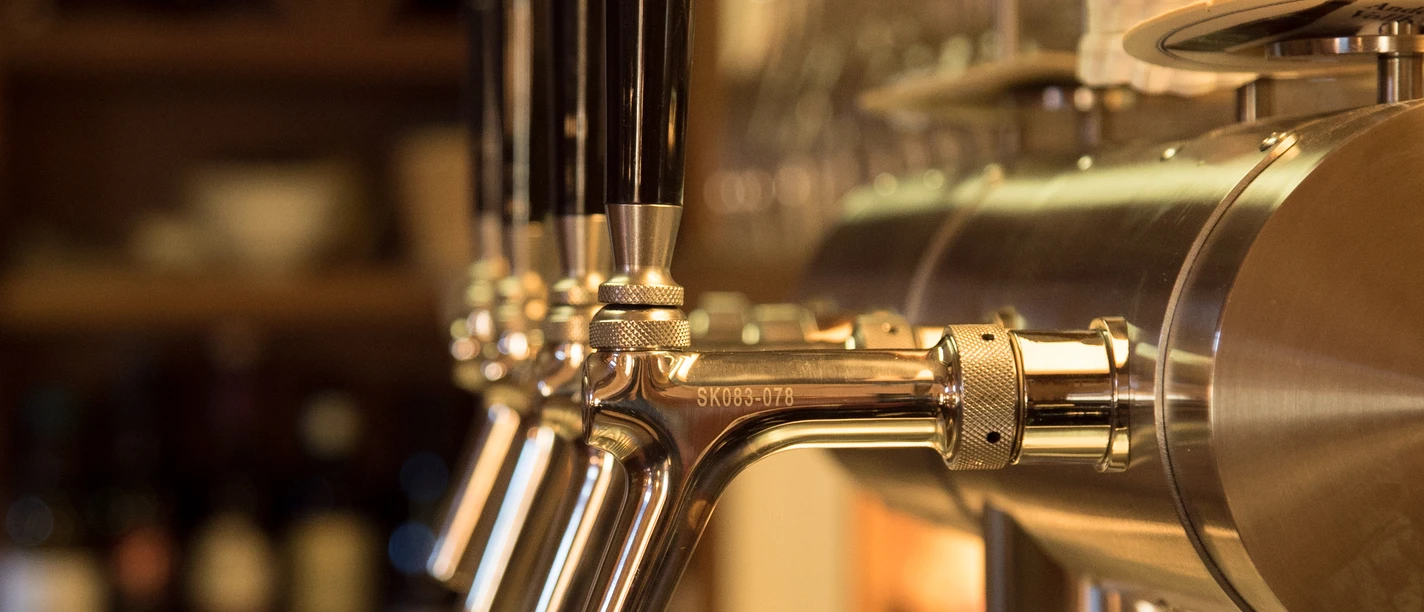 Haus Hagemeyer-Singenstroth Reihen von glänzenden Bierzapfanlagen mit dunklen Griffen in einem stimmungsvollen Gastraum.