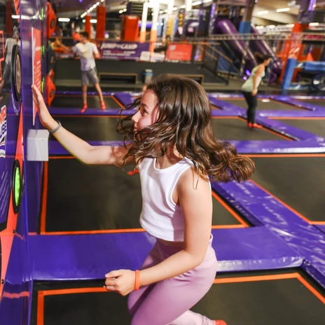 A girl jumps on a trampoline and presses glowing buttons in a reaction game at JUMP House Leipzig, leisure, family, excursion