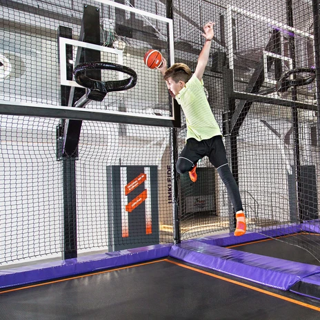 A boy jumps on a trampoline with a basketball to a basketball hoop at JUMP House Leipzig, Family, Outing, Leisure time