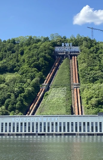Hengsteysee Hagen.jpg Kraftwerk Koepchenwerk am Hengsteysee, umgeben von grünen Hügeln unter blauem Himmel mit weißen Wolken.