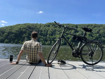 Steg am Hengsteysee.jpg Eine Person sitzt entspannt mit einem Fahrrad auf einem Steg am Hengsteysee und blickt über das Wasser.
