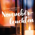 novemberleuchten_2025.JPG Kerze in Laterne strahlt warmes Licht aus, Hintergrund zeigt Einladung zu "Novemberleuchten".