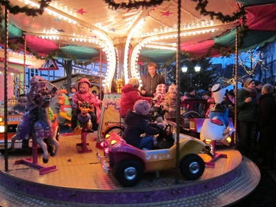 weihnachtsmarkt_lügde.JPG Kinder genießen eine fröhliche Fahrt auf einem hell erleuchteten Karussell bei einem Weihnachtsmarkt.