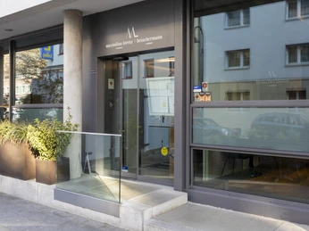 Restaurant Maximilian Lorenz Die gläserne Fassade des Restaurants Maximilian Lorenz in Köln spiegelt das urbane Lebensgefühl wider, während der schmale Eingangsbereich zum innovativen Dining-Erlebnis einlädt. Pflanzendekoration setzt grüne Akzente.The glass façade of the Maximilian Lorenz restaurant in Cologne reflects the urban lifestyle, while the narrow entrance area invites guests to enjoy an innovative dining experience. Plant decorations add green accents.