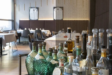 Restaurant Maximilian Lorenz Das Restaurant Maximilian Lorenz in Köln, stilvoll eingerichtet mit eleganten Sitzecken und einem Vordergrund voller edler Getränkeflaschen.