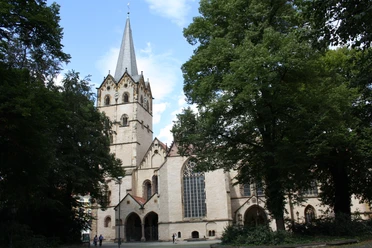 IMG_2607.JPG Historische Kirche mit hohem Turm und gotischen Fenstern umgeben von grünen Bäumen bei sonnigem Wetter.