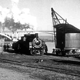 Dampflok-Weser.jpg Historische Dampflok vor Eisenbahnbrücke am Fluss in Schwarz-Weiß, Dampf steigt aus dem Schornstein empor.