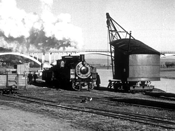 Dampflok-Weser.jpg Historische Dampflok vor Eisenbahnbrücke am Fluss in Schwarz-Weiß, Dampf steigt aus dem Schornstein empor.