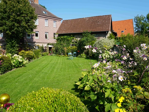Gutshof ehemaliges Herrenhaus Vorgarten.JPG Rückseite des mit Sandsteinschindeln verkleideten Herrenhaus Lütmarsen mit Garten