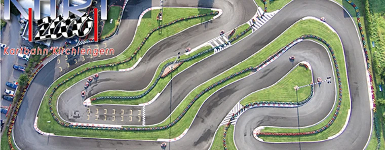 Luftaufnahme einer kurvenreichen Outdoor-Kartbahn mit mehreren Streckenabschnitten und grüner Umgebung.