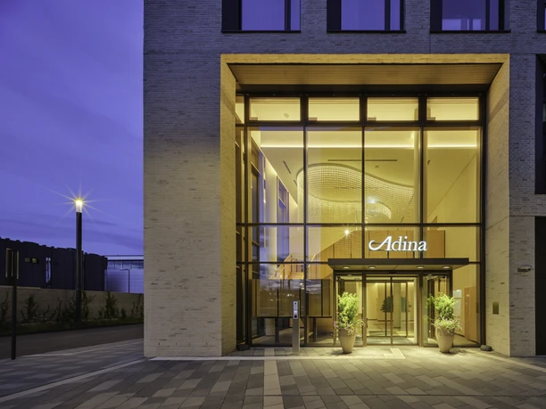 Adina-Hotel-Cologne Entrance to the Adina Hotel in Cologne with bright lighting and modern architecture.