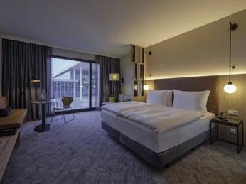 Adina-Hotel-Room Helles Hotelzimmer mit großen Fenstern und Doppelbett, modern eingerichtet für einen angenehmen Aufenthalt.Bright hotel room with large windows and double bed, modern furnishings for a pleasant stay.