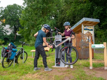Zwei Frauen an kleiner Servicestation zum Selberreparieren für Fahrräder