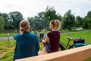 Zwei Frauen auf einer Bank mit Blick zur Weser und Fahrrädern