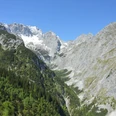 Blick vom Höllental bis hinauf auf die Zugspitze - und mittendrin die Höllentalangerhütte Weitreichendes alpines Tal mit Felswänden, grünen Hängen und schneebedecktem Gipfel.