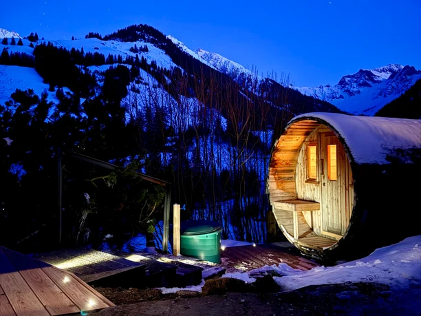 Sauna en tonneau éclairé à l'extérieur la nuit