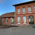 Infoterminal Stolzenau am alten Bahnhof Historisches Backsteingebäude mit Infoterminal, umgeben von einem gepflasterten Vorplatz unter blauem Himmel.