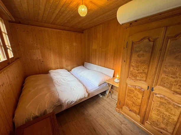 Kleine Schlafzimmer mit Doppelbett Kleines, holzgetäfertes Schlafzimmer mit Bett und Holzschrank