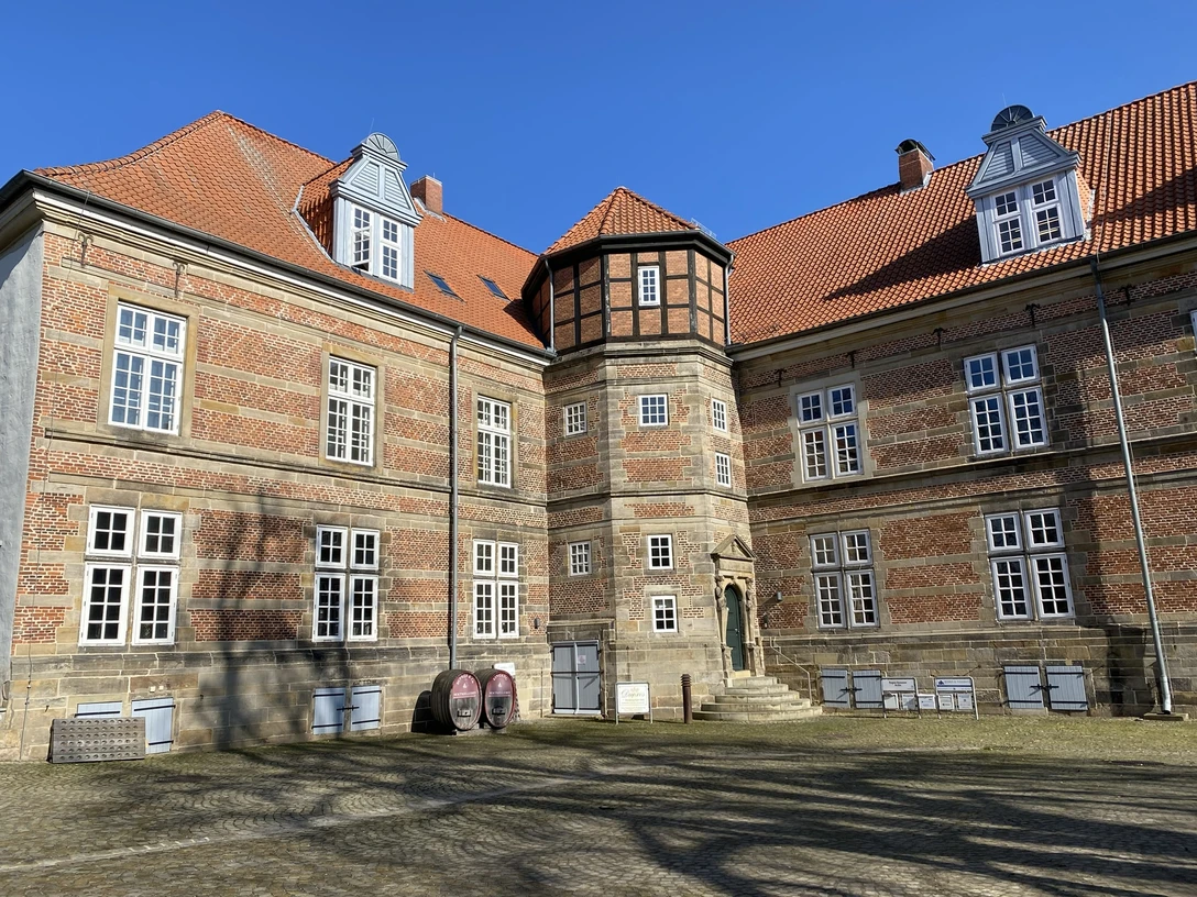Schloss Landestrost Ein historisches Schloss mit Backsteinfassade und markantem Turm vor strahlend blauem Himmel.