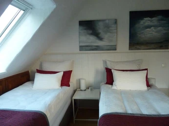 P1070270-800x600_Bei-Veronica_3.jpg Zwei helle Einzelbetten in einem Dachzimmer mit schräger Decke, moderner Kunst an der Wand.
