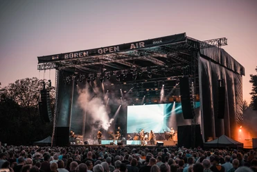 BOA Rocks Großes Freiluftkonzert bei Sonnenuntergang mit Künstlern auf der Bühne und Publikum im Vordergrund.