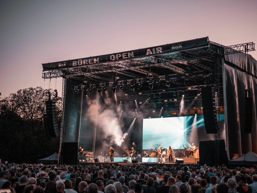 BOA Rocks Großes Freiluftkonzert bei Sonnenuntergang mit Künstlern auf der Bühne und Publikum im Vordergrund.